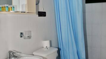 Une salle de bain avec un lavabo blanc, des toilettes et un rideau de douche bleu.