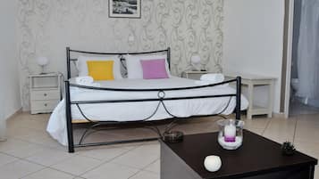 A neatly arranged bedroom with a bed, bedside tables, a small table with a candle, and a picture on the wall.