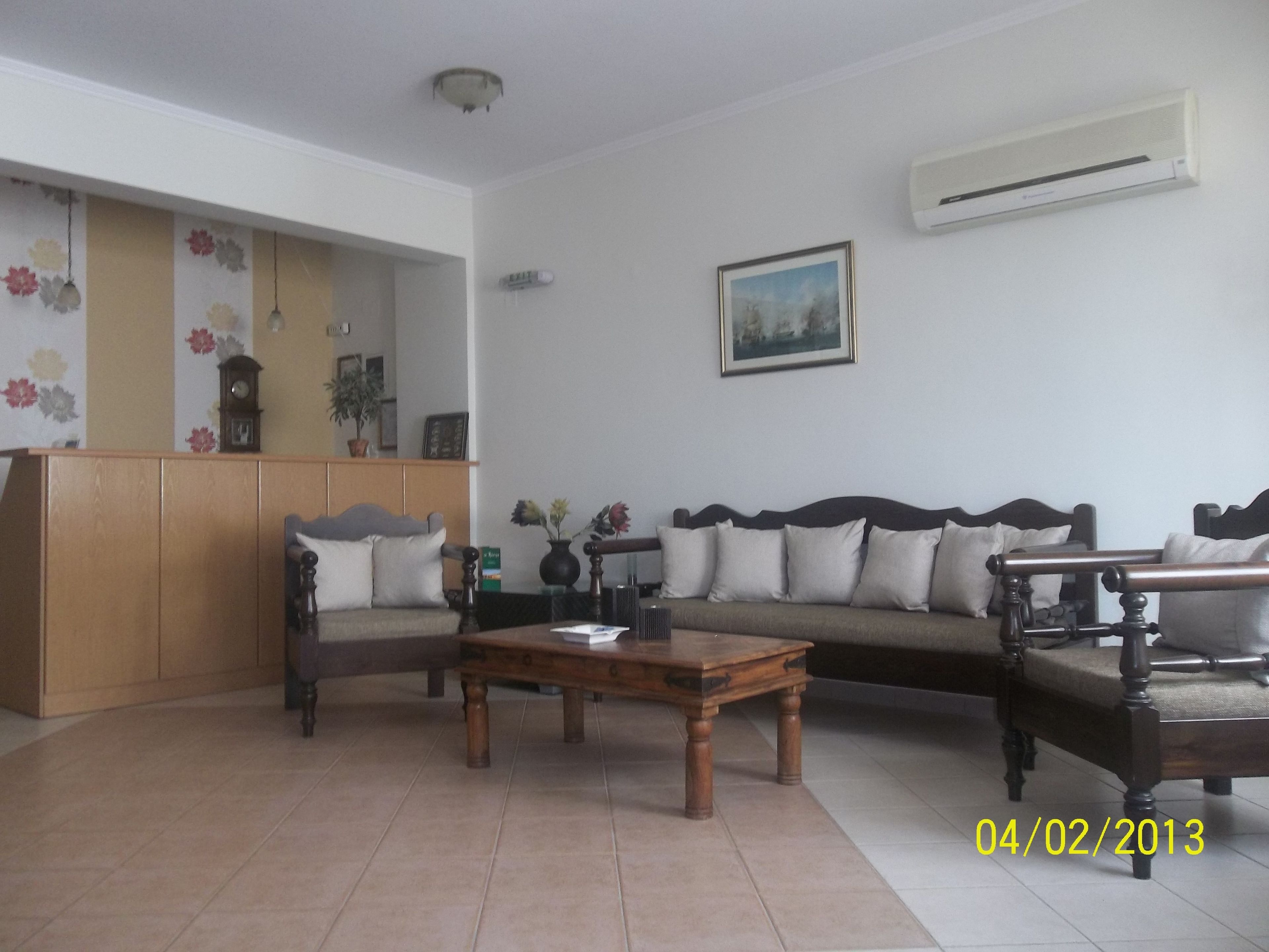 Una sala de estar con un sofá, dos sillones, una mesa de centro de madera, un reloj y un cuadro en la pared.