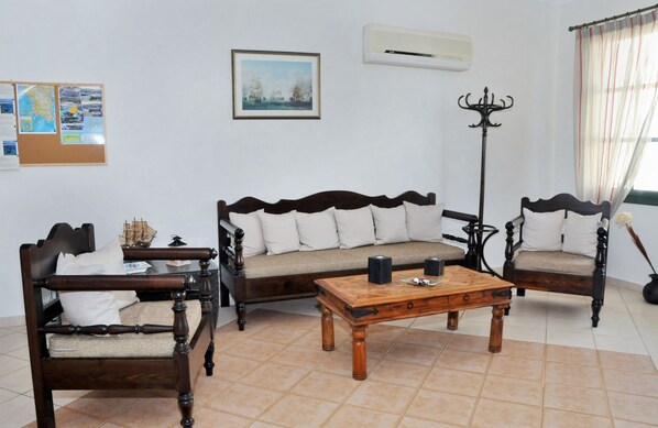 A traditional room with a sofa set, a wooden coffee table, a side table, and a floor lamp. - Kastro Hotel (Pylos-Nestoras)