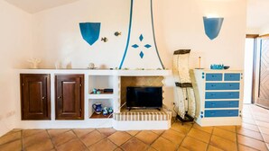 Una sala de estar con chimenea, armarios de madera, televisor y un mueble azul con cajones.