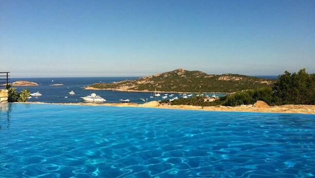Una piscina con agua cristalina, vista al mar y una isla distante.