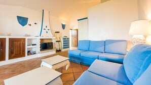 Una sala de estar con un sofá azul, una mesa de centro blanca y una chimenea.