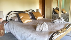 Ein ordentlich bezogenes Bett mit Kopfteil, Kissen und einem Bademantel.