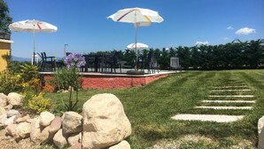 Eine Außenpatio-Terrasse mit Steintreppen, die zu einem Sitzbereich mit Sonnenschirmen führen.