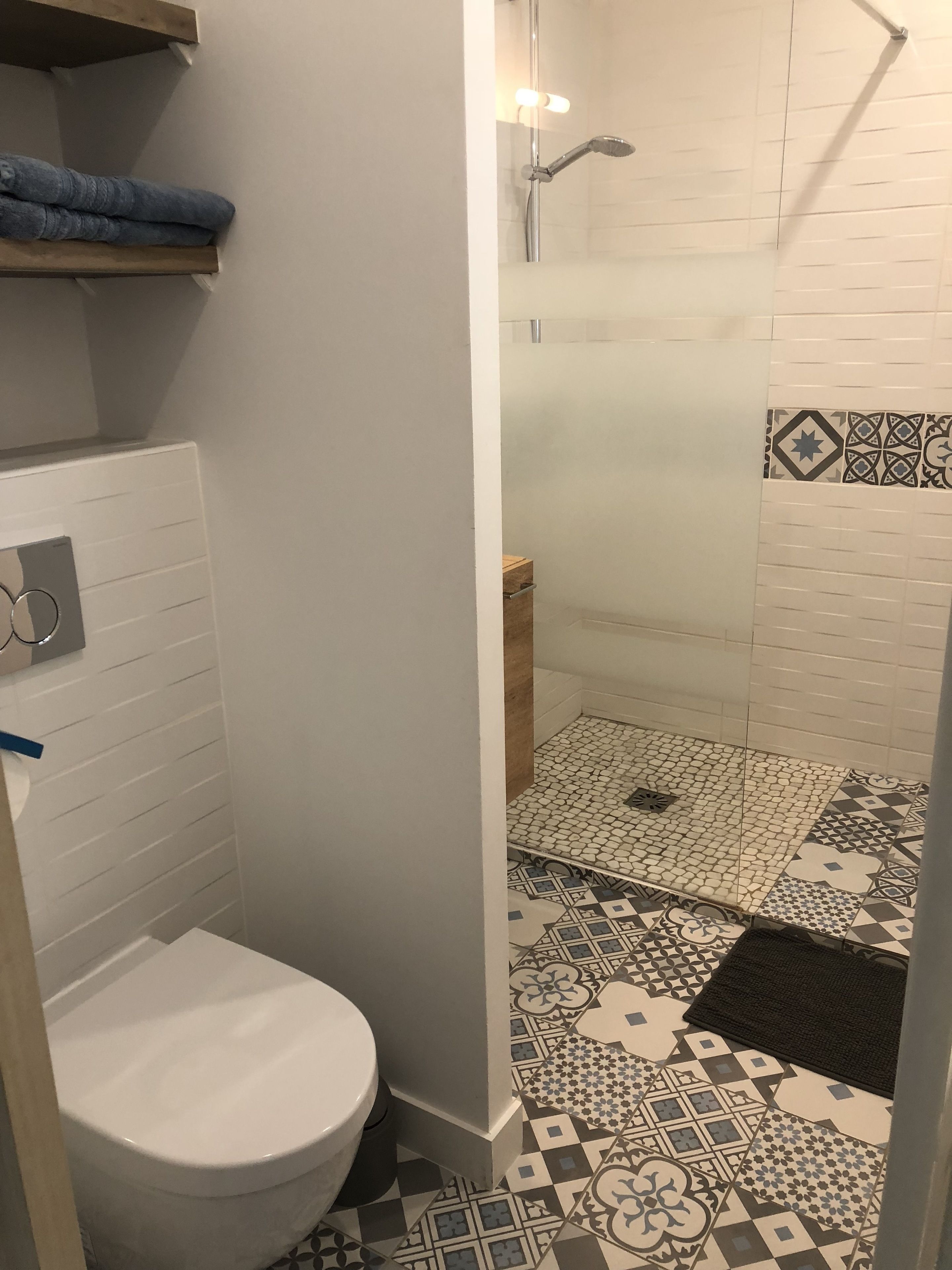 Et badeværelse med toilet, bruser og tapetfliser.