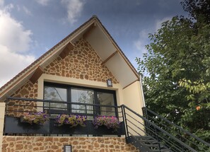 A building with a stone facade, a large window, and a balcony with flower boxes. - Chambre d'hôtes La Bourdonnaise (Bourdonne)