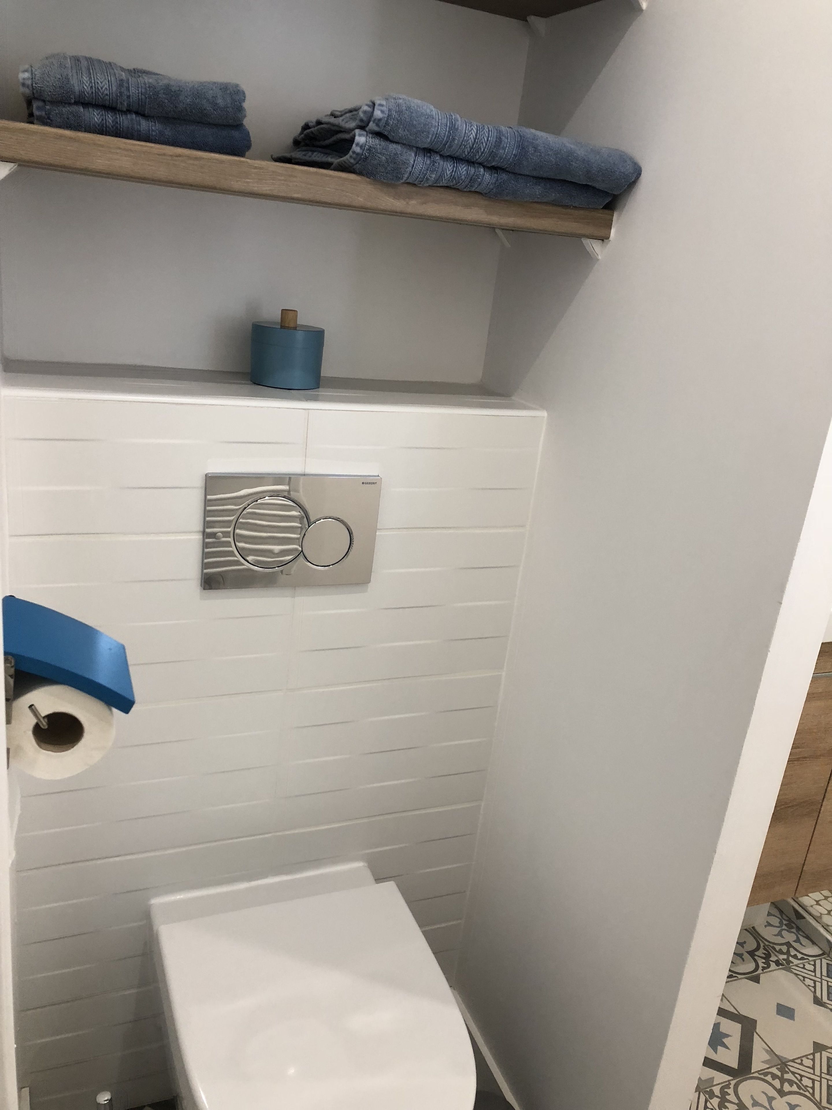 Un baño pequeño con inodoro, un perchero con toallas dobladas y un dispensador de papel higiénico.