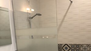 A modern bathroom with a glass-enclosed shower, a wooden vanity, and patterned tiles. - Chambre d'hôtes La Bourdonnaise (Bourdonne)