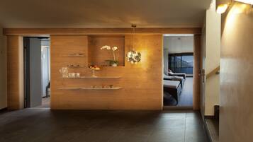 A modern interior with a wooden reception desk, a view of a mountain, and a glass door leading to a balcony.