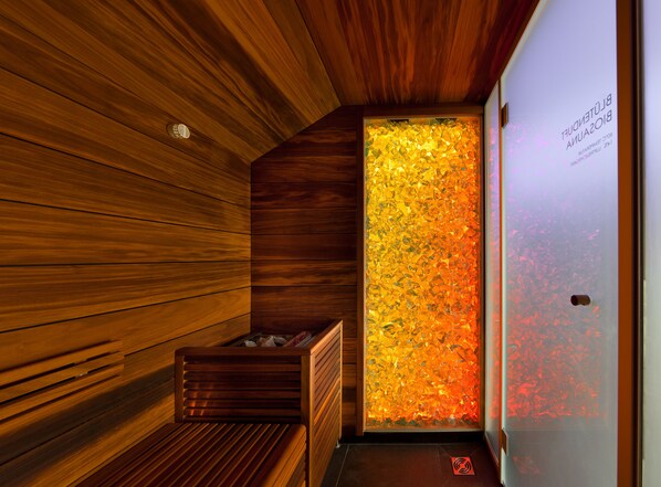A wooden sauna with a glass wall displaying colorful patterns.