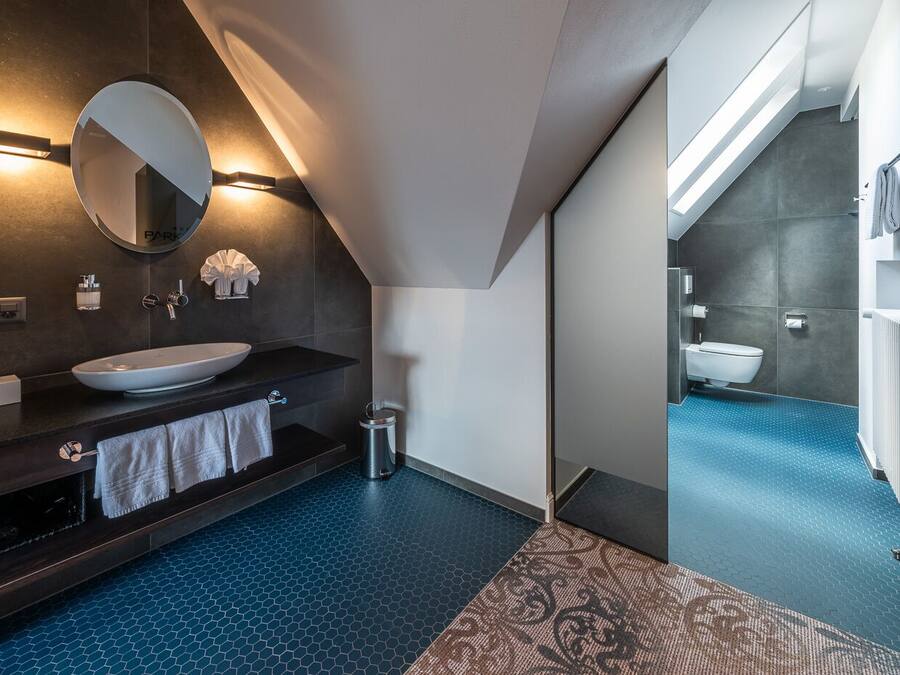 A modern bathroom with a large mirror, a round sink, and a dark countertop.