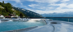 A hot tub with a mountain view, surrounded by buildings and a lake.