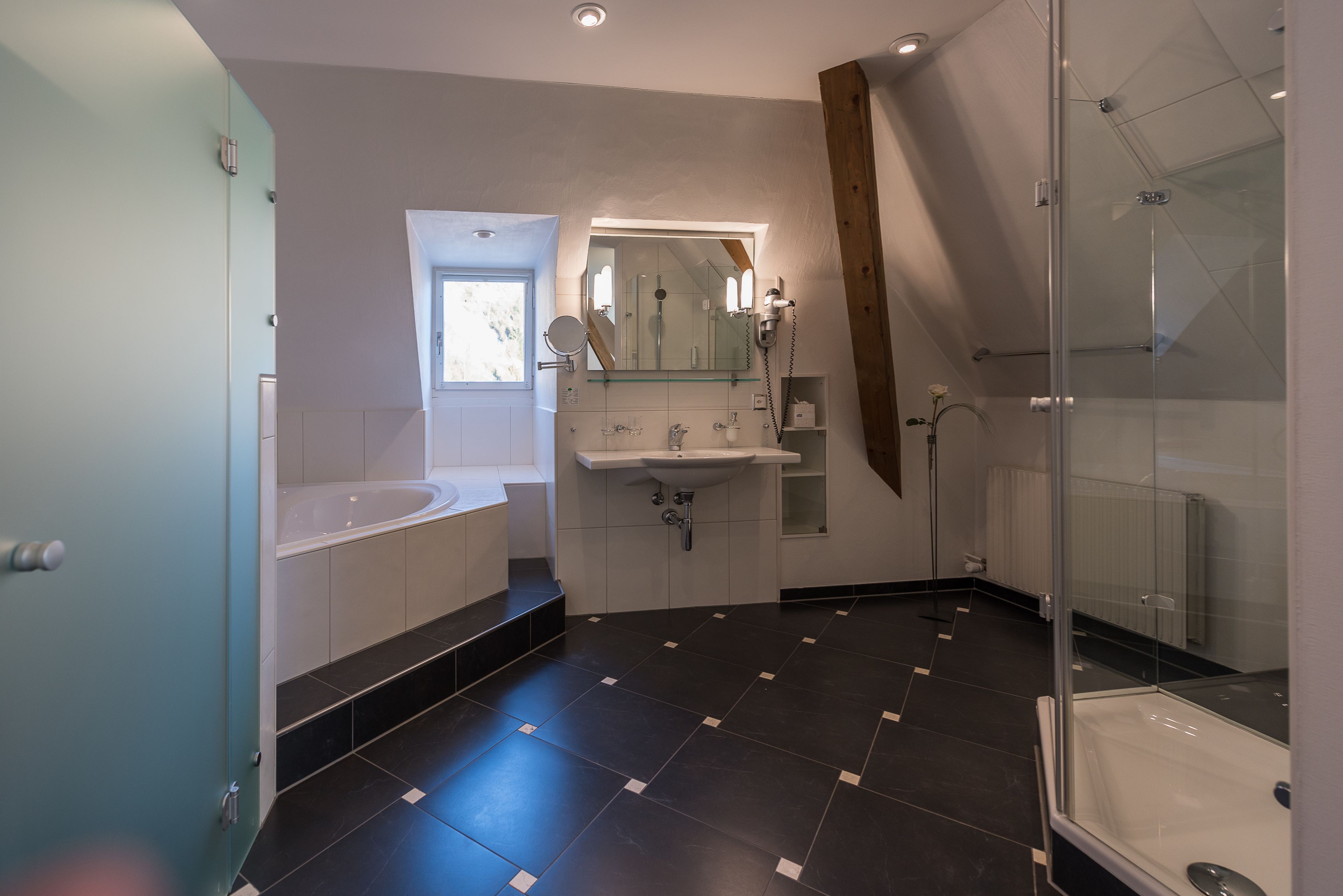Une salle de bain moderne avec une baignoire, une douche à parois de verre et un meuble-lavabo avec un miroir.