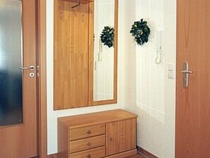 A wooden wardrobe with two doors and a small bench underneath.