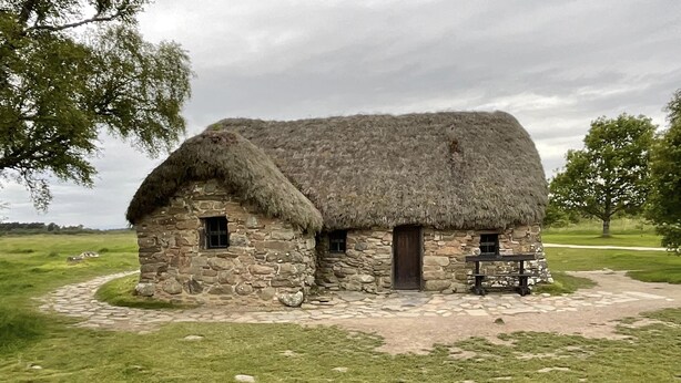 A stone cottage with a thatched roof, a small window, and a door. - Broomlea (Inverness)