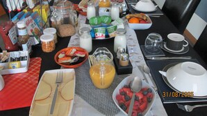 A breakfast table set with various food items, including fruits, cereals, and dairy products. - Broomlea (Inverness)