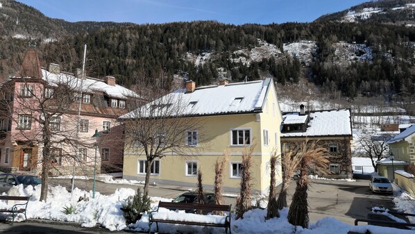 A residential area with snow-covered houses, a street, and a mountain backdrop.