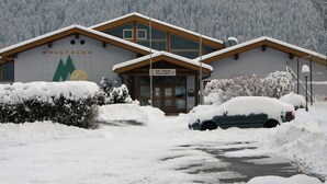 Un edifici amb un rètol que diu "Molltaler" i "Cafè - Pizzeria Tennissstüberl". La neu cobreix el terra i hi ha cotxes aparcats.