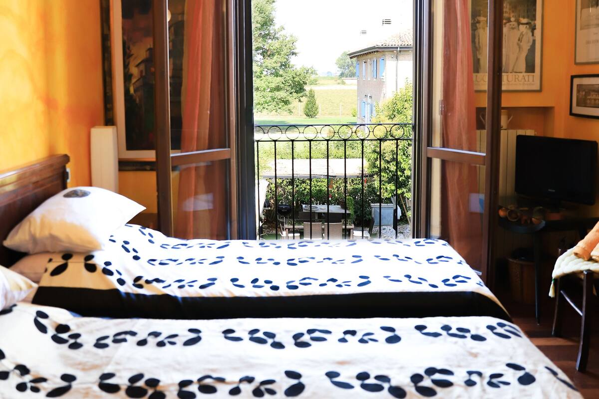 Une chambre d’hôtel avec deux lits, une télévision et un balcon donnant sur l’extérieur.