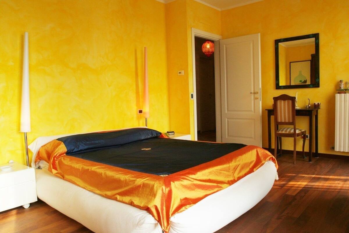 Une pièce comprenant un lit, une chaise, un bureau et un miroir.
