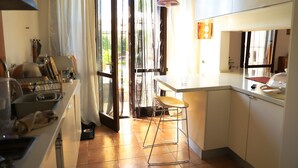 Une cuisine comprenant un coin repas, un évier et une fenêtre avec des rideaux.