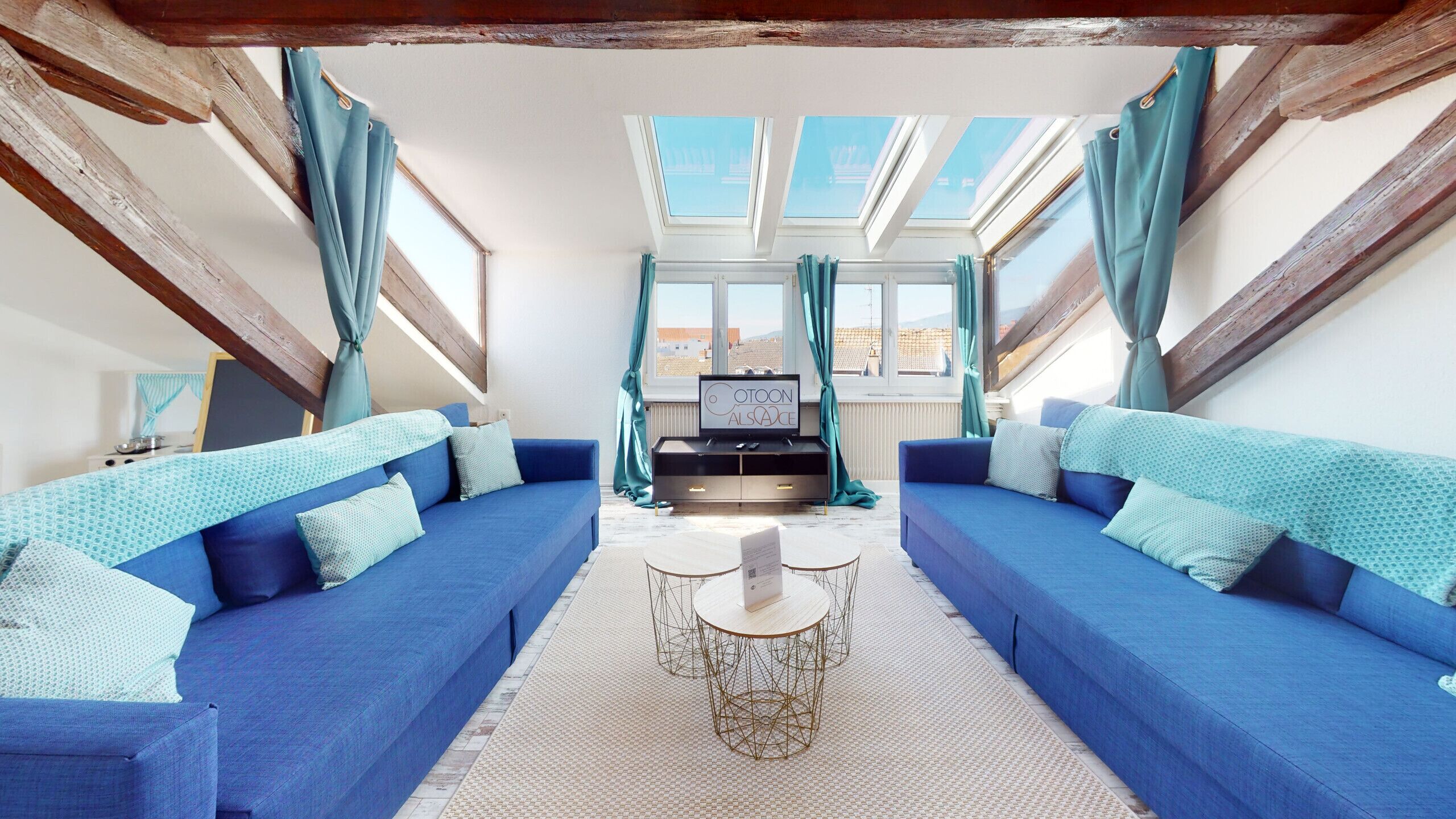 A modern living room with a blue sofa set, a coffee table, and a TV on a black stand.
