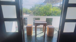 An open doorway leading to a balcony with a table and two wooden stools. - Chrish Residence (Negombo)