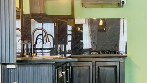A kitchen with a black countertop, dark cabinets, and a green wall. - Chrish Residence (Negombo)