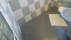 A bathroom with a checkered tile pattern, a toilet, a sink, and a shower area. - Chrish Residence (Negombo)