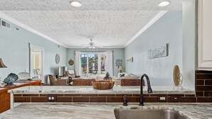A kitchen with a marble countertop, a sink, and a dining area with wicker furniture.