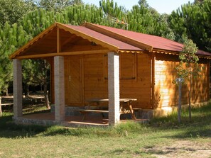 Eine Holzhütte mit rotem Dach, einer Veranda und einem Ziegelmauerwerk.