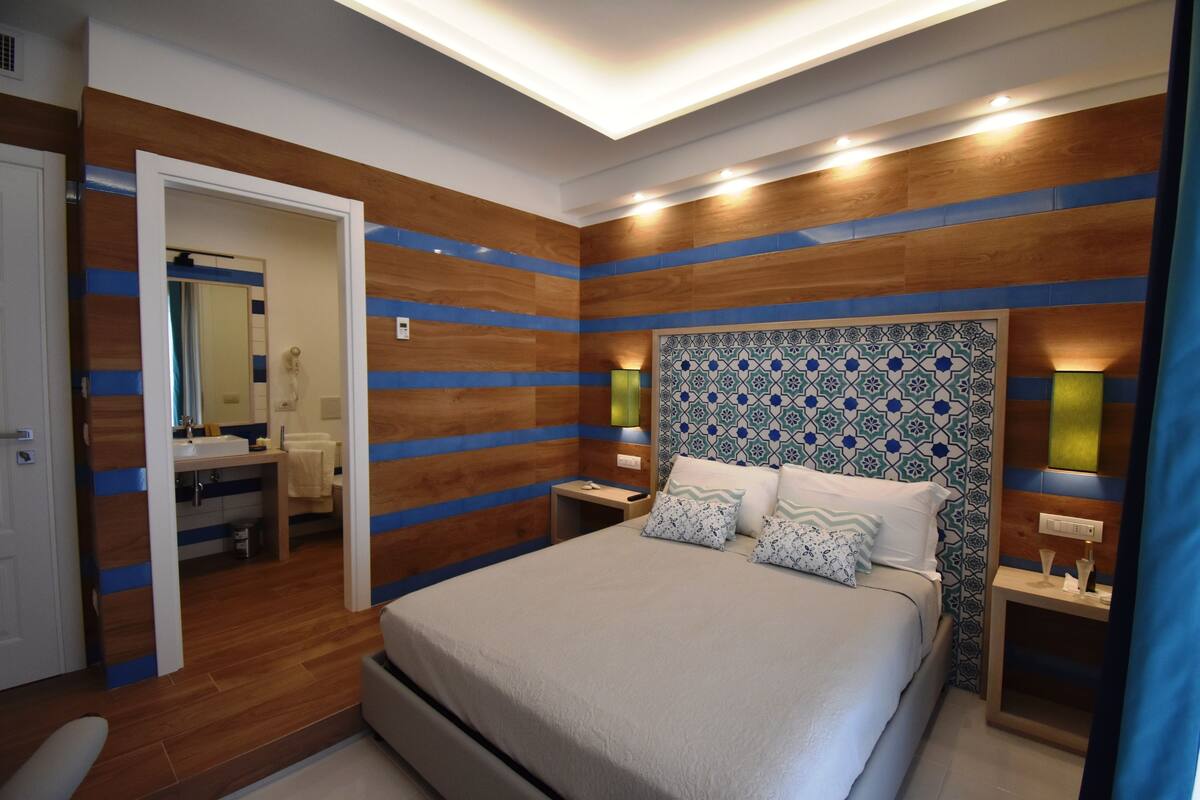 Een moderne slaapkamer met een groot bed, houten paneelwanden en een gestreept hoofdeinde.