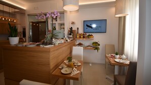 Un espace repas moderne avec un comptoir en bois, des sièges et un téléviseur diffusant l'émission « Melody Suites ».