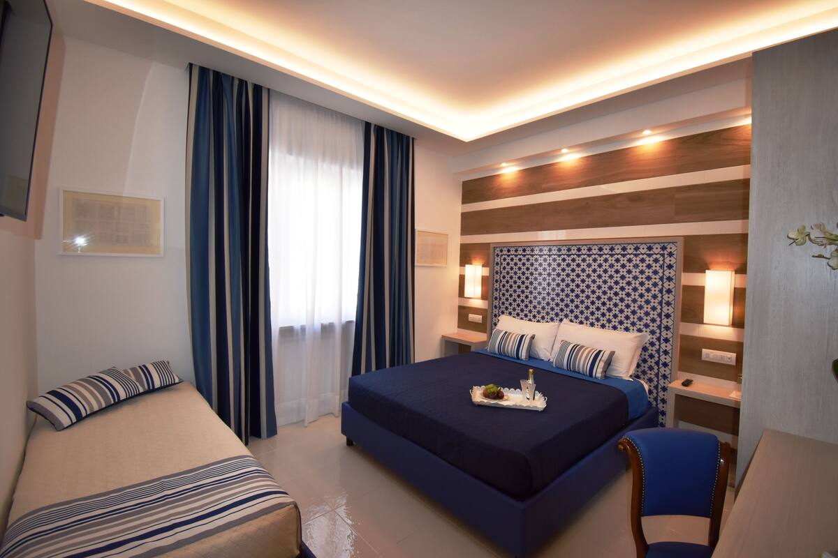 Een hotelkamer met een groot bed, een kleiner bed, een bureau en een stoel.