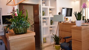 Une chambre d’hôtel moderne, dotée d’un comptoir d’accueil en bois, d’une télévision et de divers éléments décoratifs, notamment des plantes et des vases.