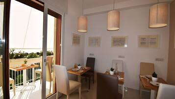 A dining area with two tables, chairs, pendant lights, and framed artwork on the walls.