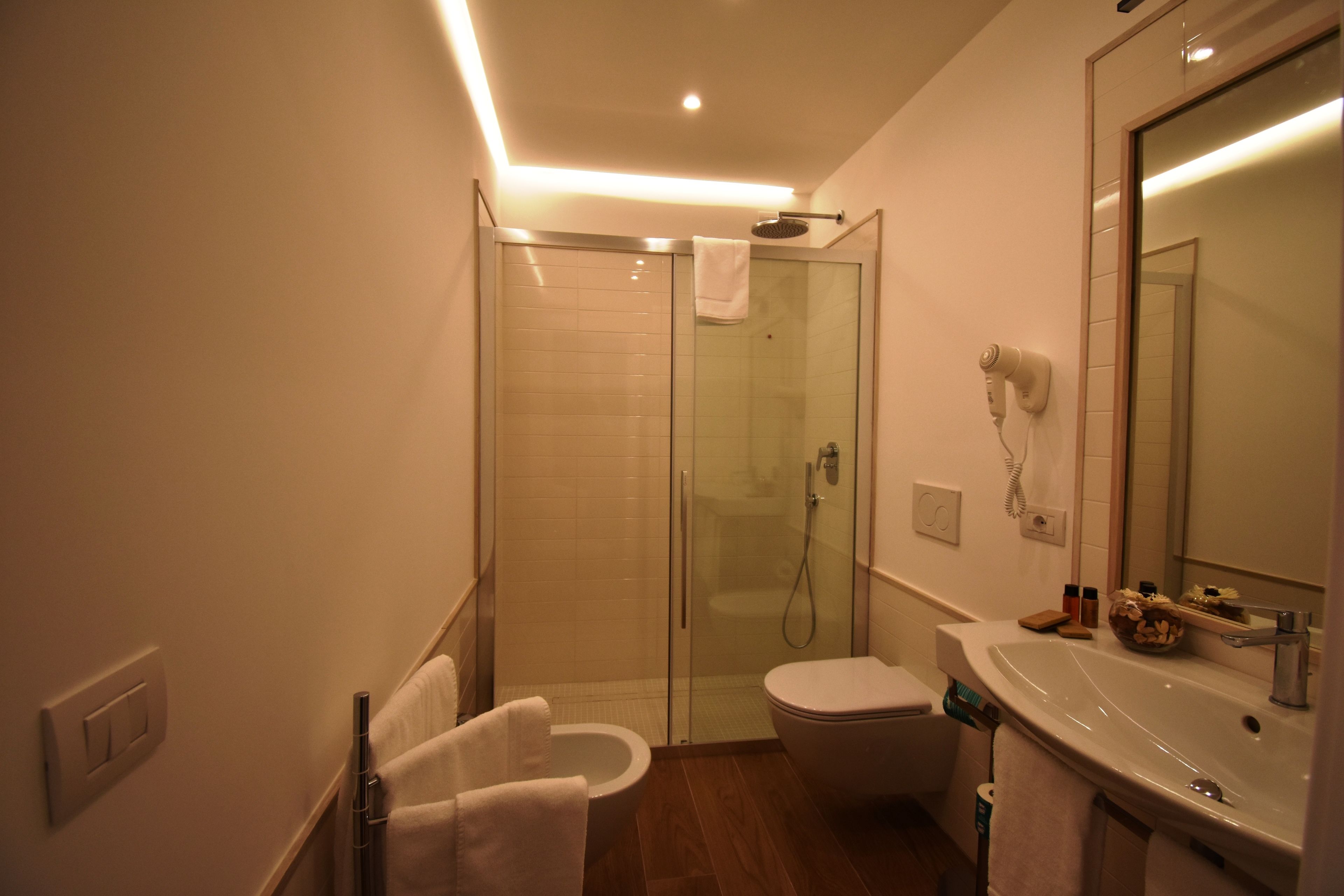 A modern bathroom with a glass-enclosed shower, a white toilet, and a sink with a mirror above it.
