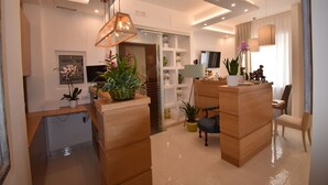 Un salon moderne avec un comptoir d’accueil en bois, un fauteuil bleu et une plante en pot.