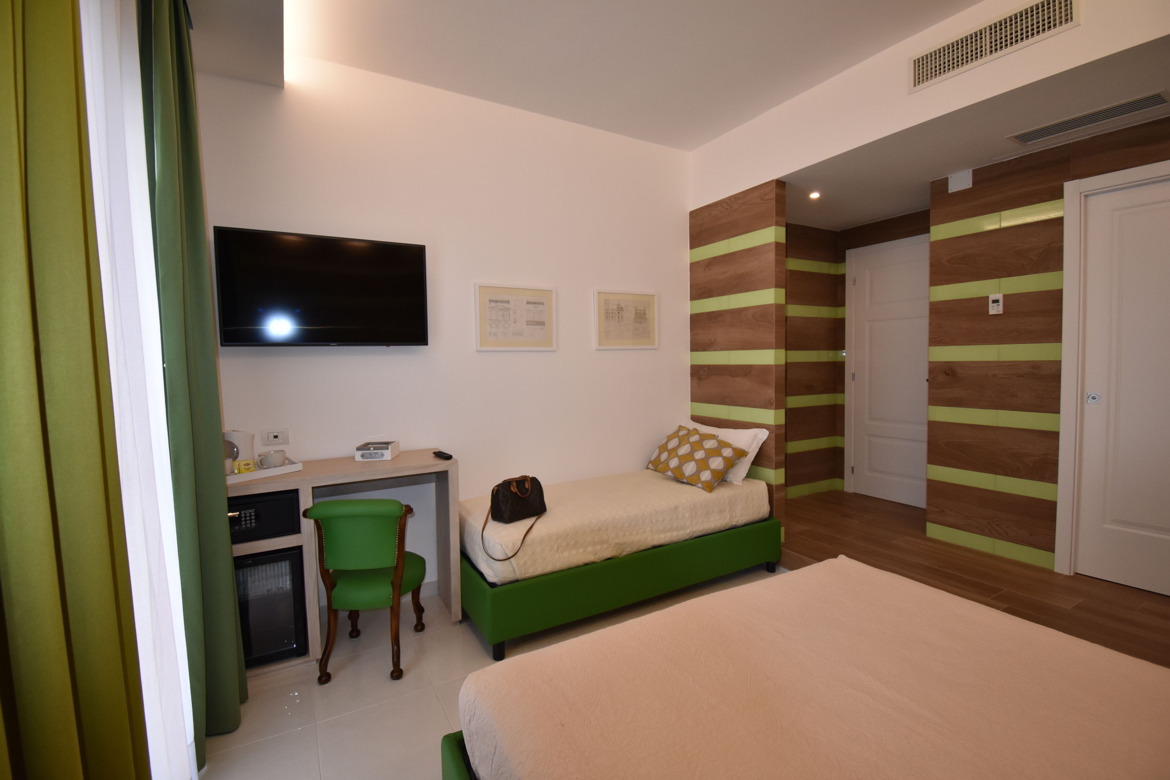 Un dormitorio con cama, escritorio, silla, televisor y puerta.