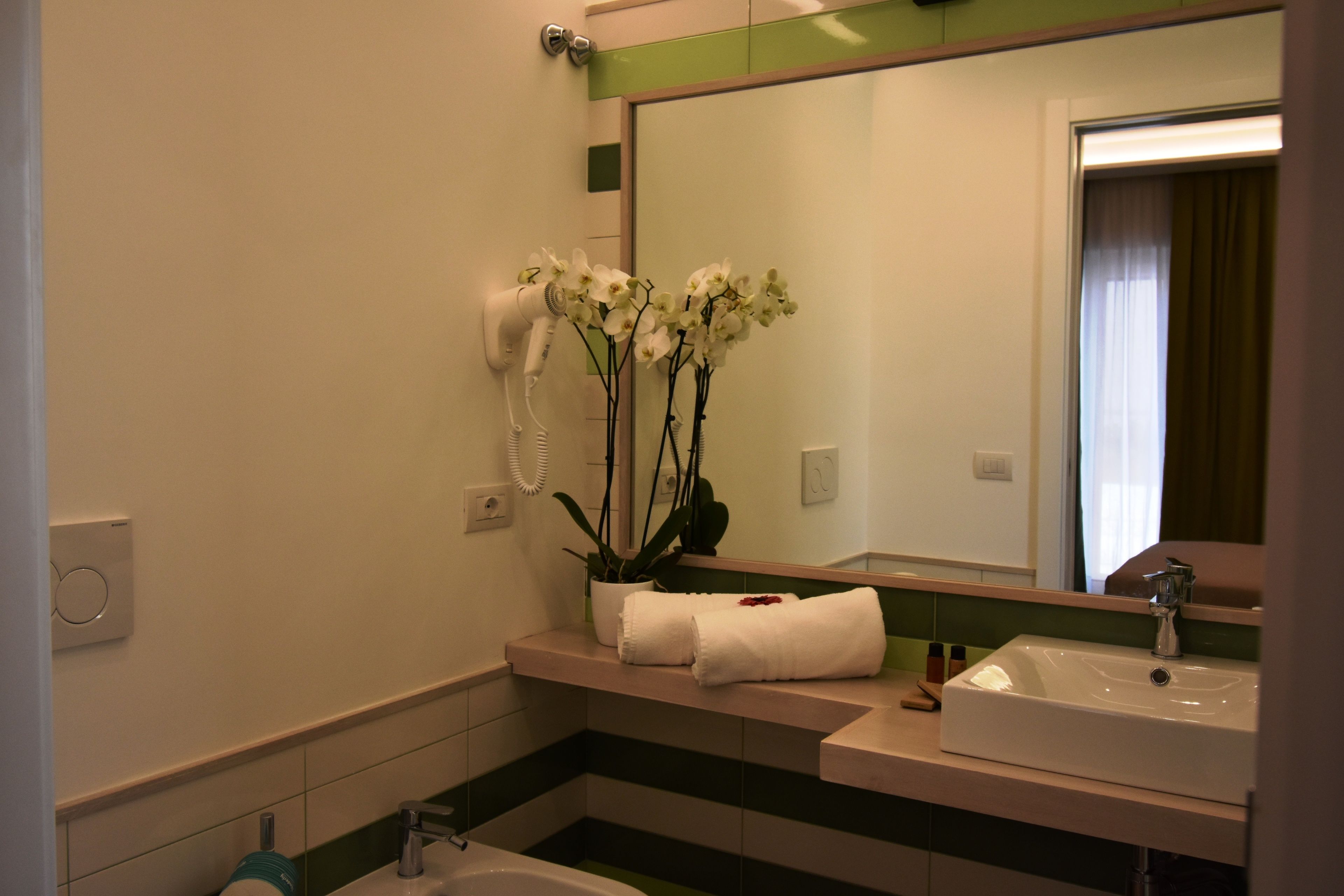 A bathroom with a sink, mirror, and a hairdryer mounted on the wall.