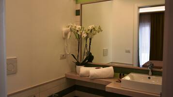 A bathroom with a sink, mirror, and a hairdryer mounted on the wall.