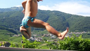 A person jumping into a pool with a mountainous landscape in the background.