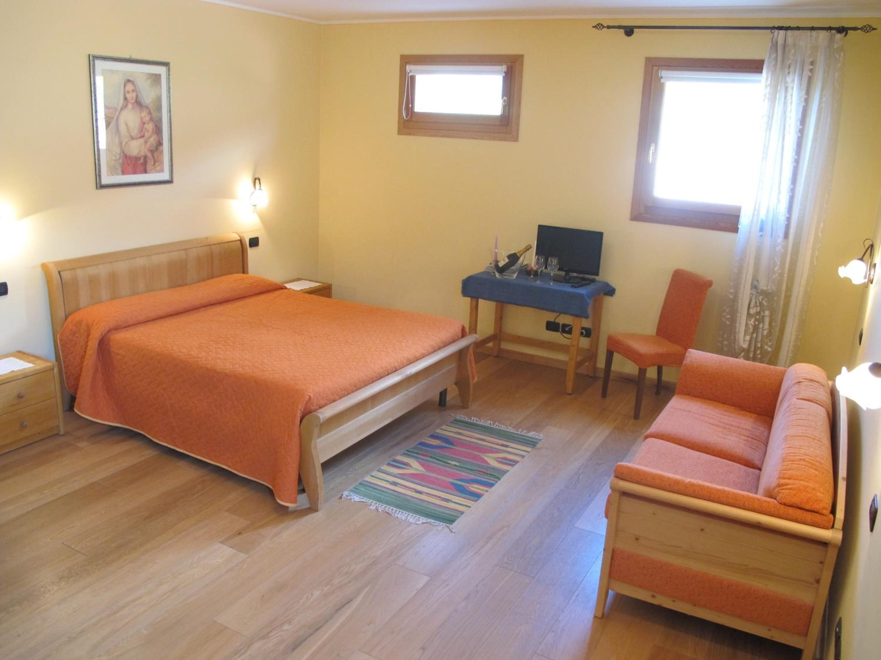 Een slaapkamer met een bed, een bureau, een stoel en een bank.