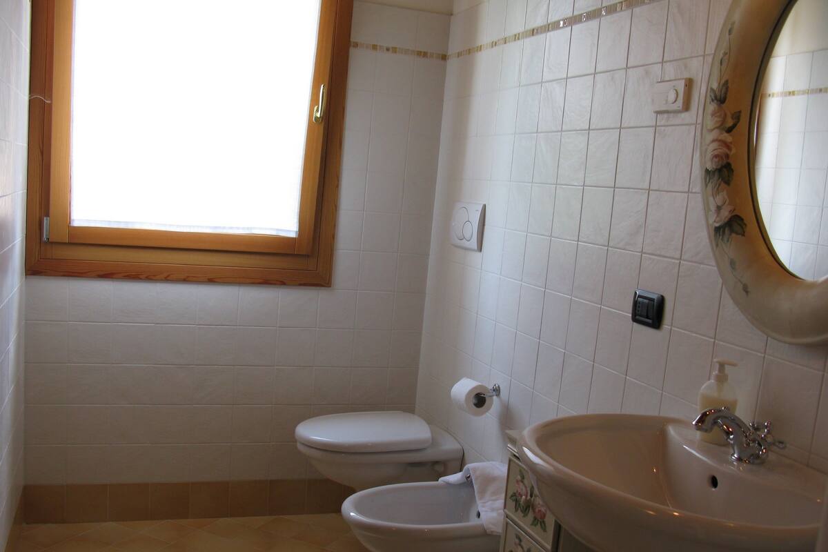 A bathroom with two toilets, a sink, and a window.