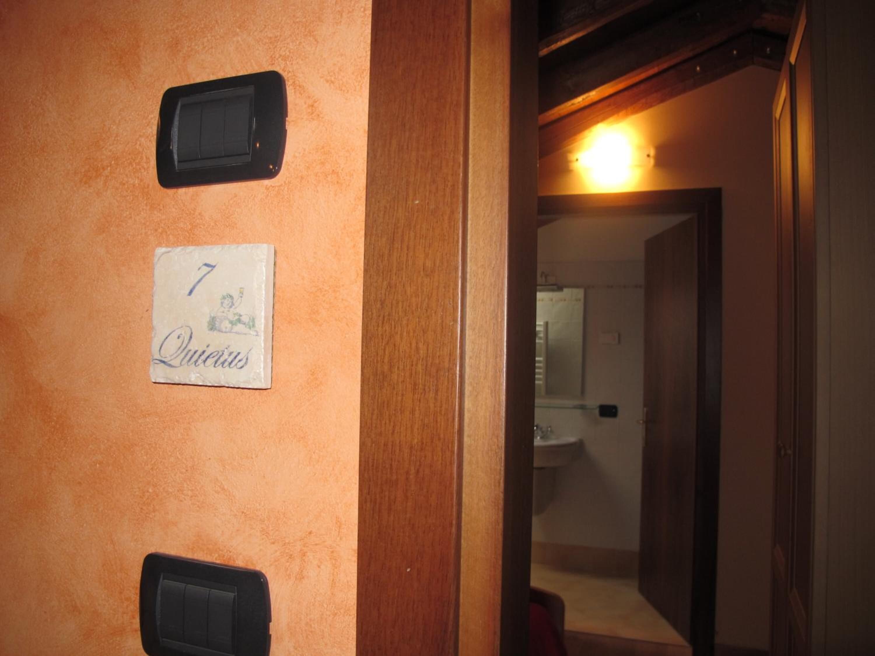Un baño con lavabo y espejo, una puerta con el símbolo de número, y una lámpara sobre el espejo.