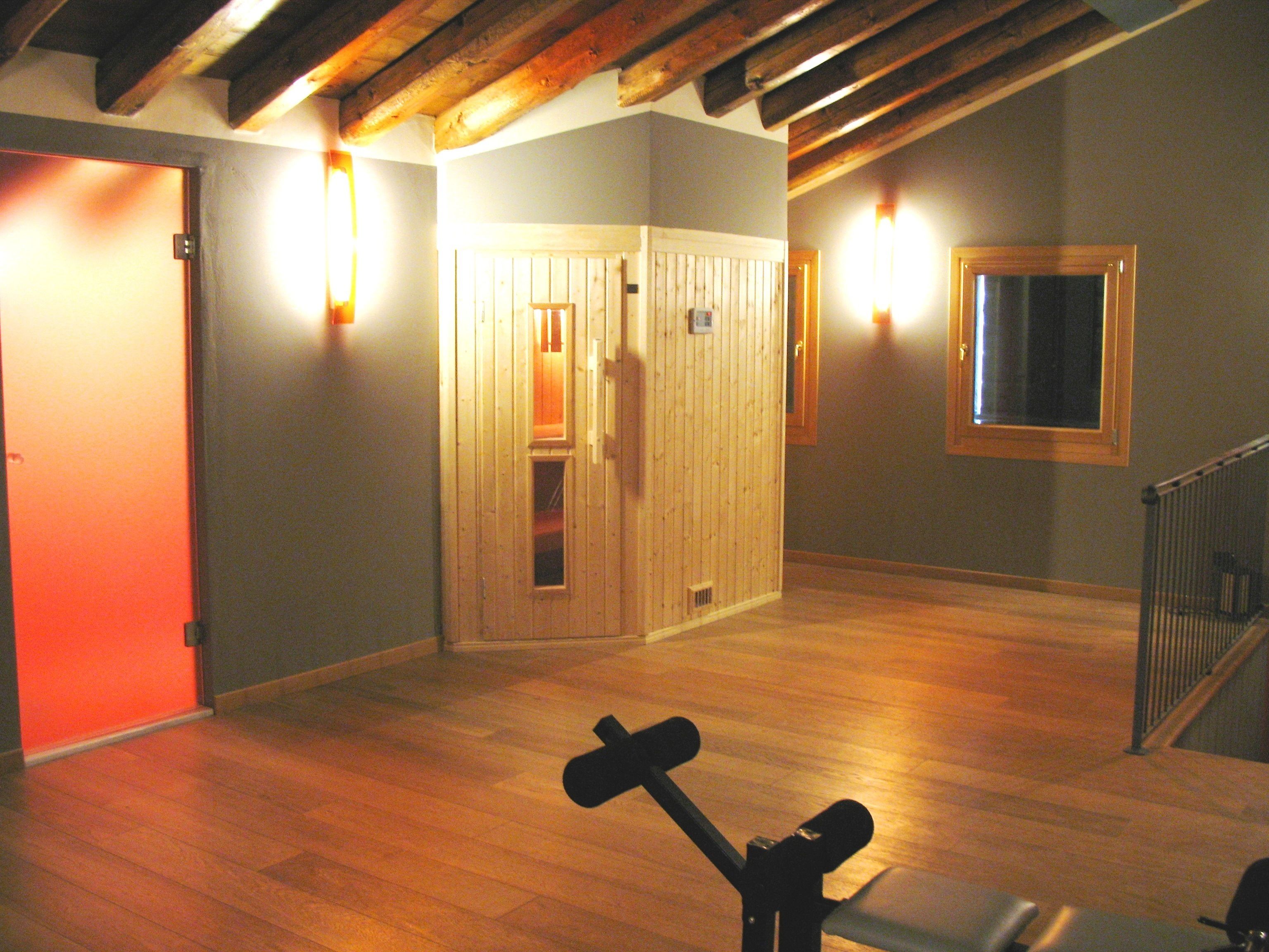 Ein geräumiges Zimmer mit Holzboden, einer Tür und einer an der Wand befestigten Leuchte.