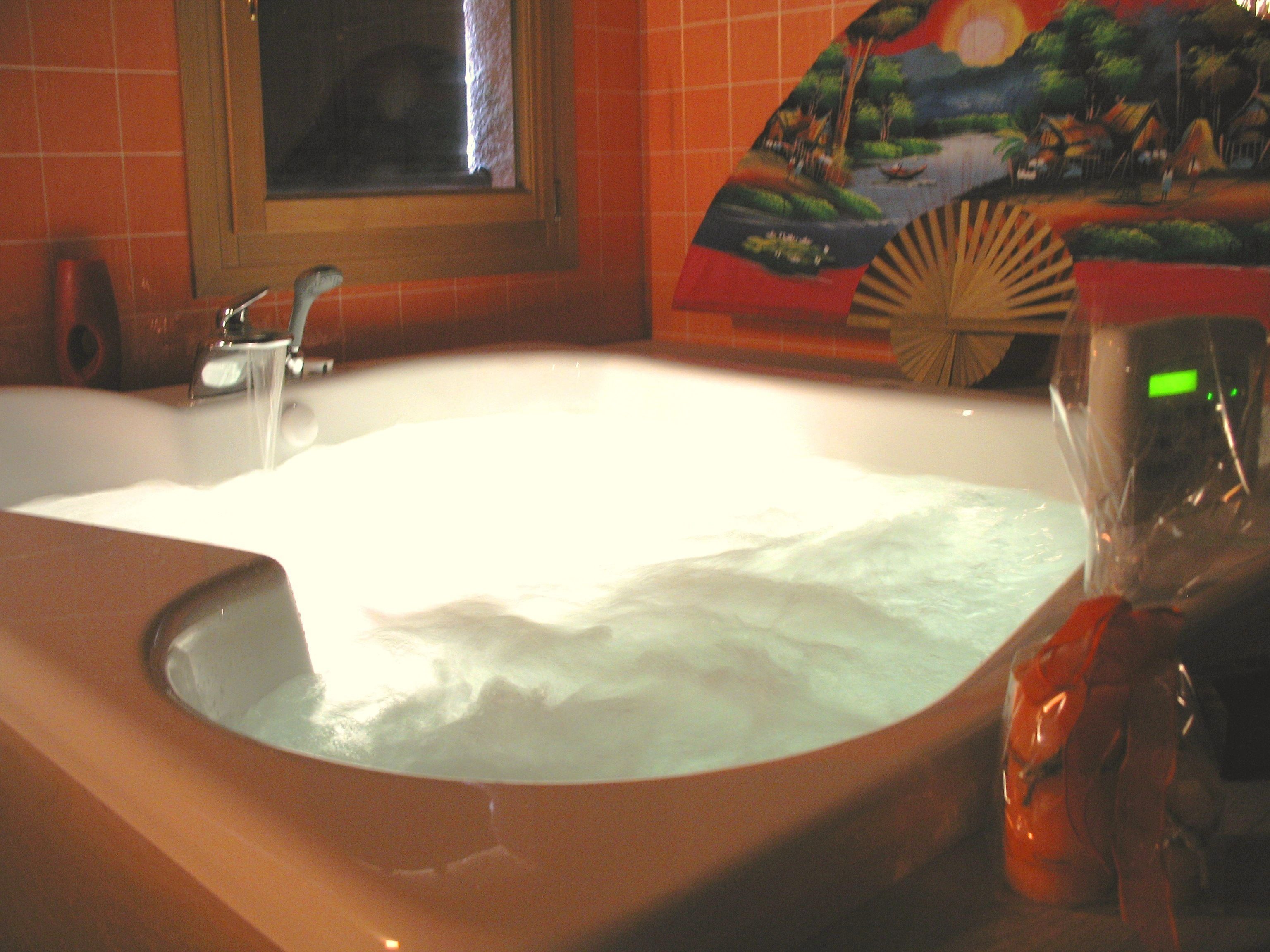 A bathroom with a bathtub, a window, and a decorative painting on the wall.
