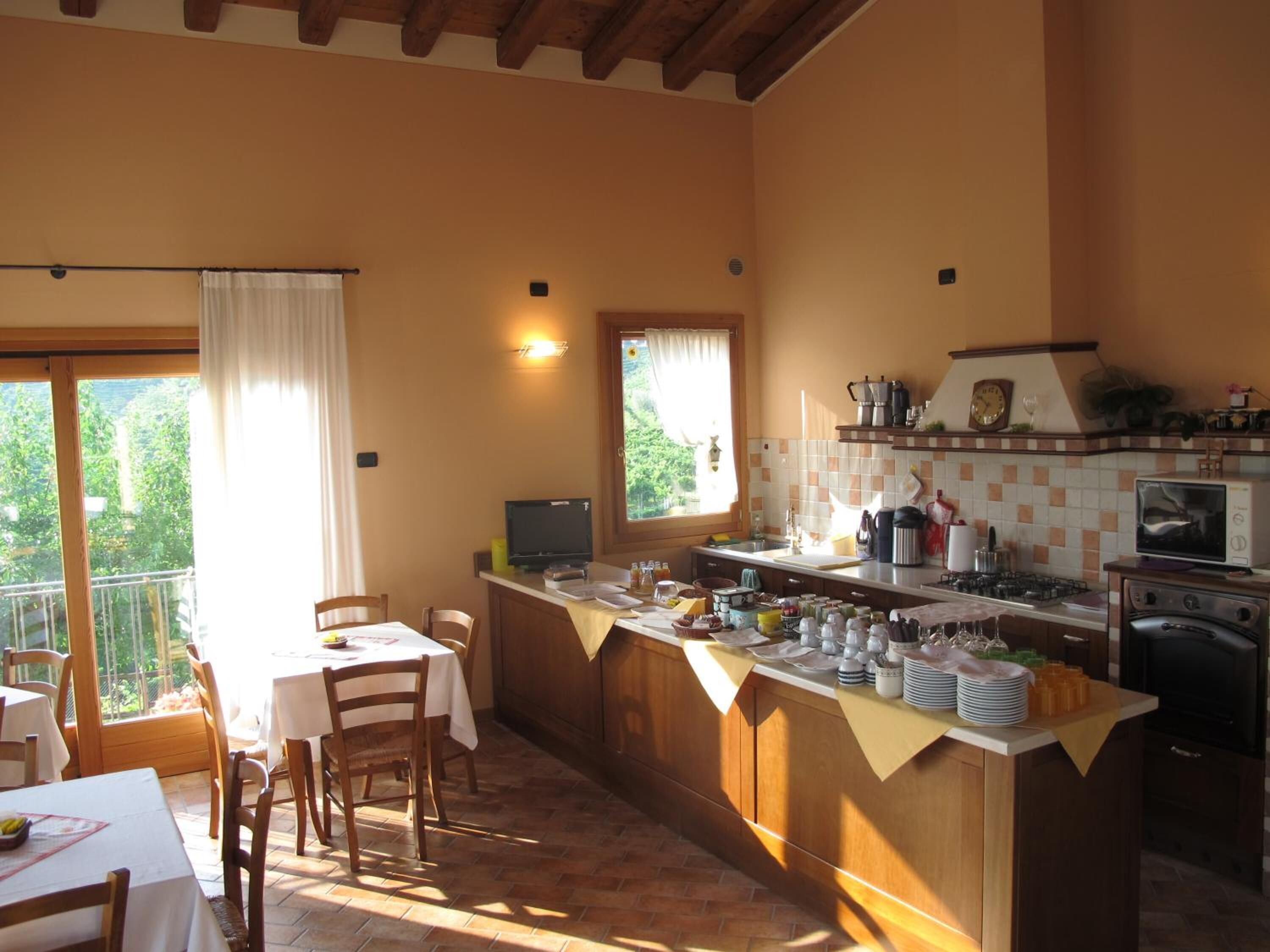 Una cocina acogedora con armarios de madera, una zona de comedor con mesa y sillas, y vistas a través del ventanal.