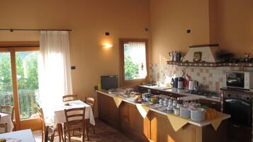 Una cocina acogedora con armarios de madera, una zona de comedor con mesa y sillas, y vistas a través del ventanal.